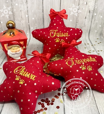 Três almofadas estrela vermelhas com nomes bordados e laços e um candeeiro decorativo vermelho
