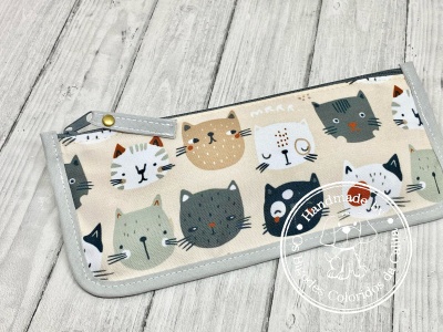 Carteira ou estojo bege com padrão de gatos coloridos e acabamento cinza