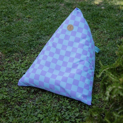 Pufe triangular lilás e azul com etiqueta redonda de couro sobre relva verde