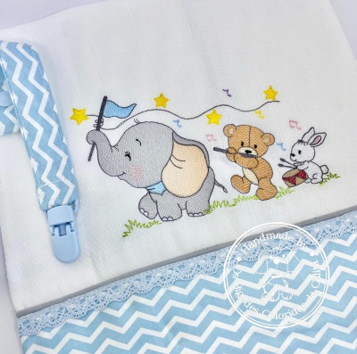 Toalha branca com bordado de elefante, urso e coelho e padrão azul em zig-zag