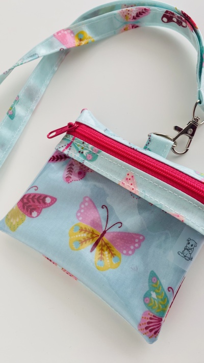 Bolsa pequena azul com padrão de borboletas e fecho rosa