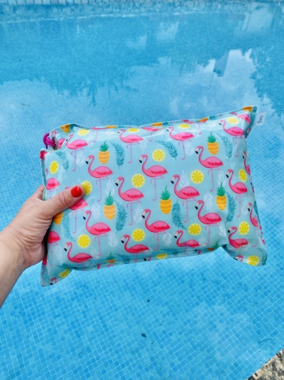 Pequena almofada azul com padrão de flamingos e frutas junto a piscina