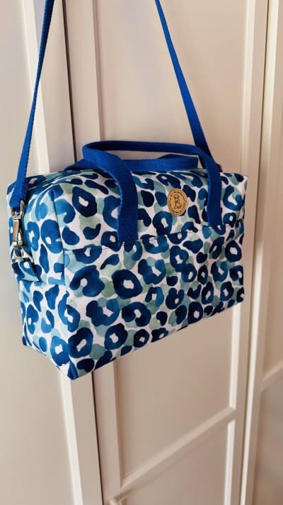 Bolsa estampada azul e verde com alças azuis e etiqueta redonda de couro