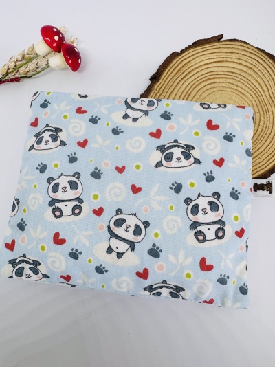 Tecido azul com estampado de pandas e corações colocado sobre superfície branca e madeira