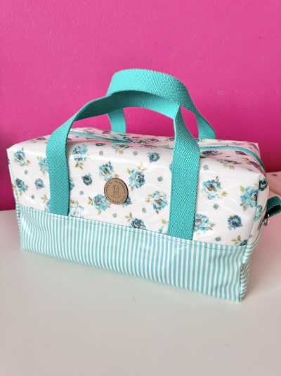 Mala retangular floral azul e branco com riscas e alças azul-turquesa
