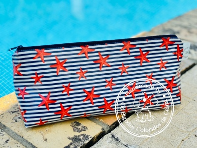 Necessaire azul com riscas brancas e estrelas do mar vermelhas perto de piscina