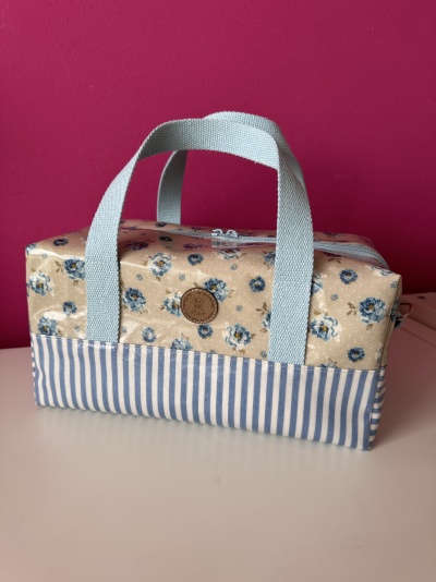 Bolsa retangular floral e riscada com duas alças azuis claras