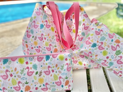 Conjunto de três acessórios de tecido com padrão colorido de flamingos e flores junto a piscina