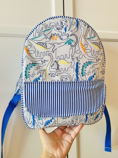 Mochila infantil com dinossauros coloridos e bolso listrado azul e branco