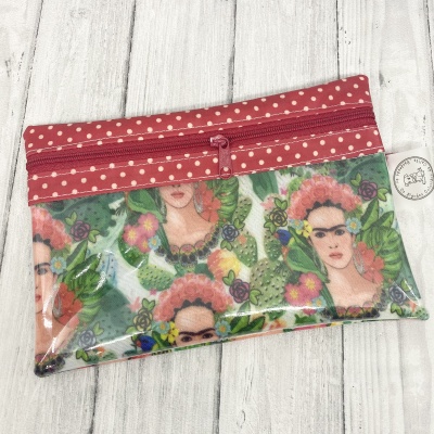 Estojo vermelho com bolinhas brancas e ilustração de Frida Kahlo com flores e folhas verdes