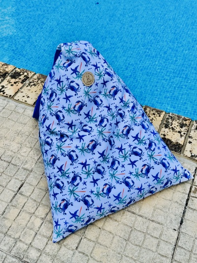 Móchila triangular com padrão de caranguejos azuis junto a piscina