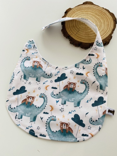 Babete para bebés com padrão de dinossauros e ursinhos sobre fundo branco