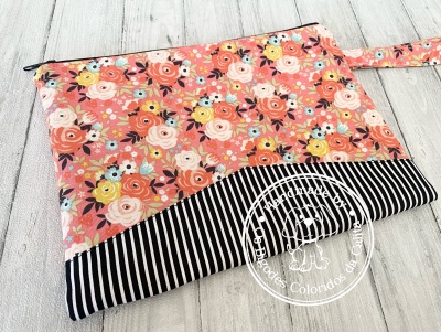 Bolsa de tecido floral com fecho e parte inferior riscada em preto e branco