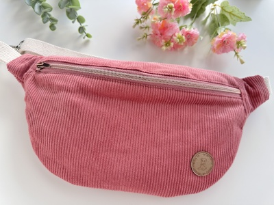 Bolsa tipo pochete rosa em veludo cotelê com fecho de correr branco e emblema redondo castanho