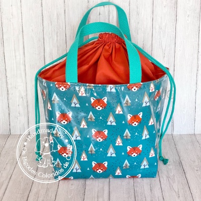 bolsa azul com padrão de raposas e árvores, alças verdes e interior laranja