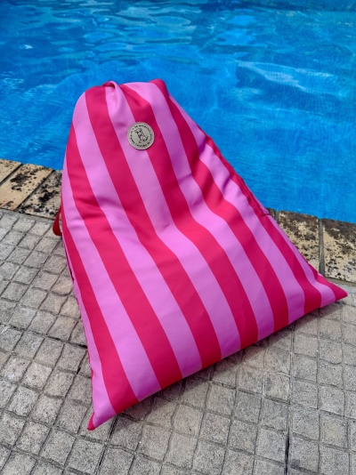 Almofada triangular riscada rosa e vermelho ao lado de piscina