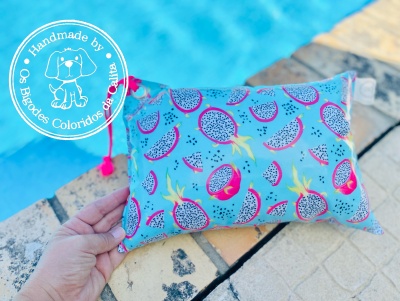 Almofada pequena azul com estampa de frutas exóticas ao lado de piscina