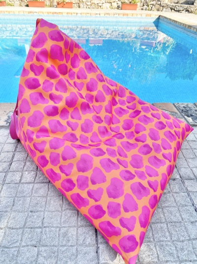 puff almofadado cor-de-rosa e laranja junto a piscina