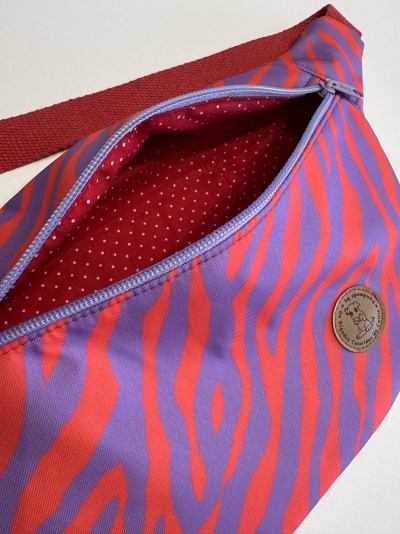Bolsa de cintura lilás com padrão vermelho e fecho lilás