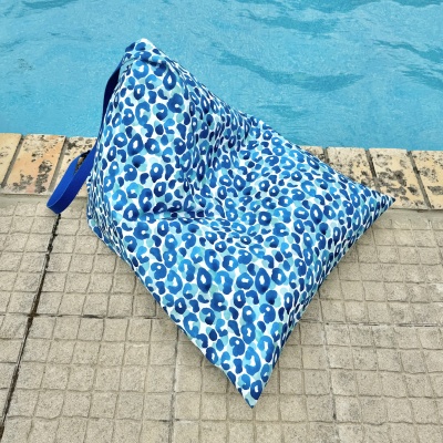 Almofada triangular azul com padrão manchado em tons de azul junto a piscina
