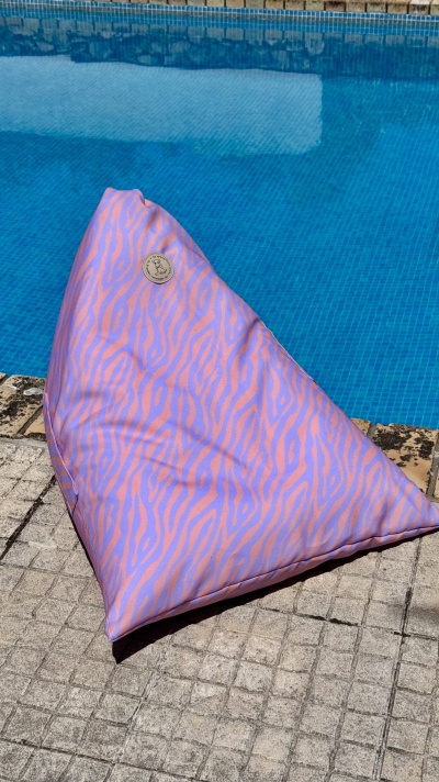 Pufe triangular rosa e lilás com padrão de zebra ao lado de piscina