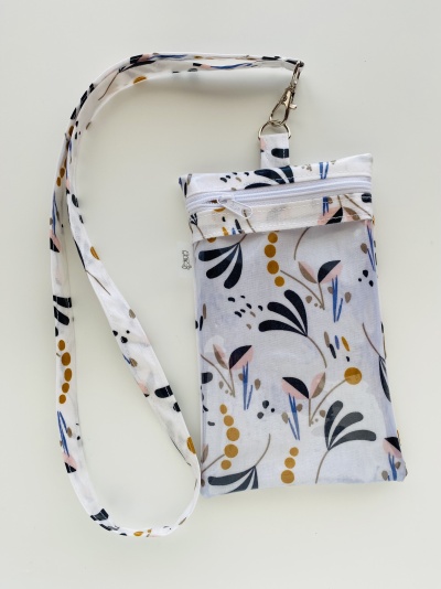 Bolsa pequena de tecido branco com padrão floral e alça destacável