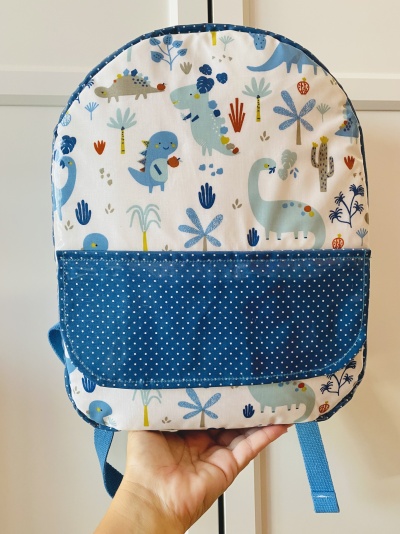 Mochila infantil com padrão de dinossauros e bolso azul estrelado