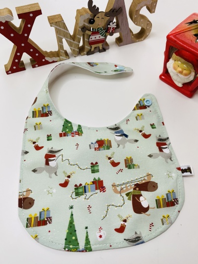 Babete com padrão de Natal e enfeites de Natal ao fundo
