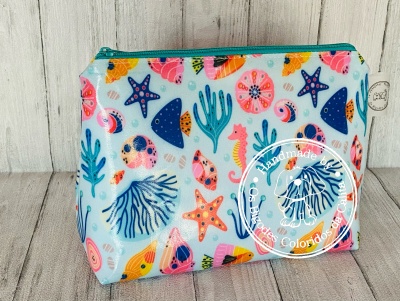 Bolsa colorida com padrão de elementos marinhos e fecho azul turquesa