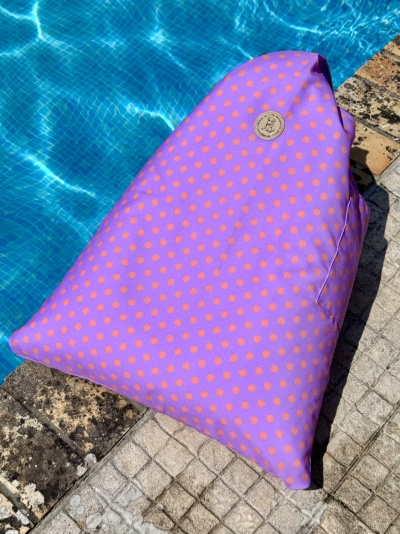 Almofada rosa com bolinhas laranja ao lado de piscina