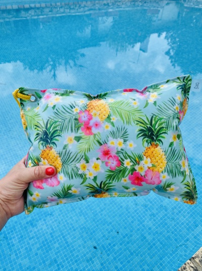 Almofada tropical colorida segurada junto a piscina