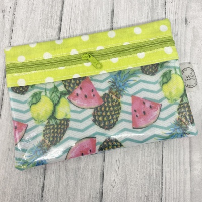 Estojo transparente com padrão de frutas e fecho verde com bolinhas