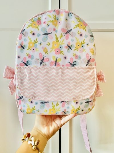 Mochila infantil floral colorida com bolso frontal em padrão zig-zag rosa e branco