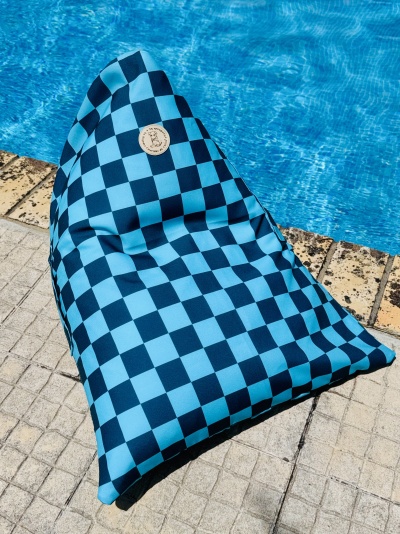 Pufe azul xadrez junto a uma piscina sobre pavimento de pedra