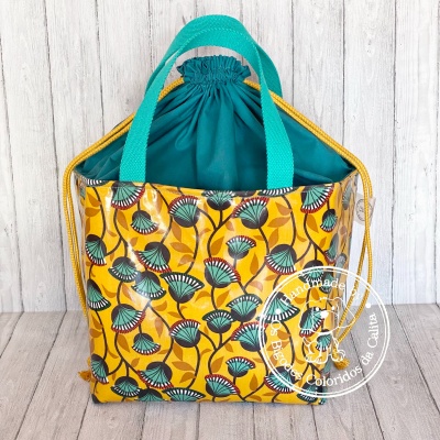 Saco de tecido amarelo com padrão floral verde e azul com alças turquesa