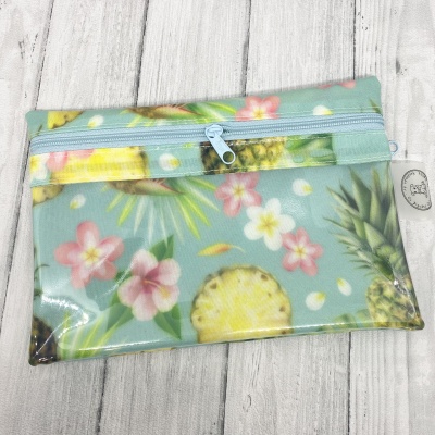 Bolsa pequena estampada com abacaxis e flores em fundo azul claro.