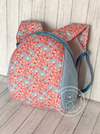 Mochila pequena em tecido azul e rosa com padrão floral e selo handmade