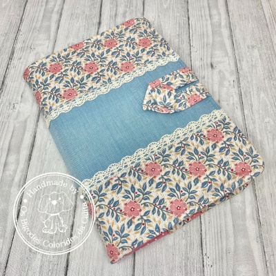 Capa de tecido floral com detalhe azul e renda sobre madeira clara