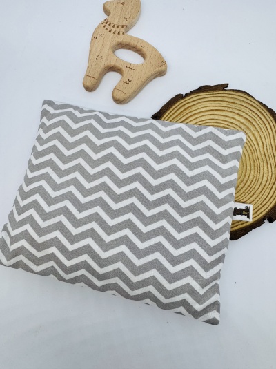 Almofada cinzenta com padrão zig-zag, brinquedo de madeira veado e suporte tronco de madeira