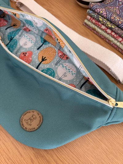 Bolsa azul com fecho creme e interior com padrão de árvores coloridas