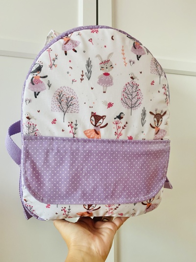 Mochila infantil lilás com padrão de animais e árvores em tecido