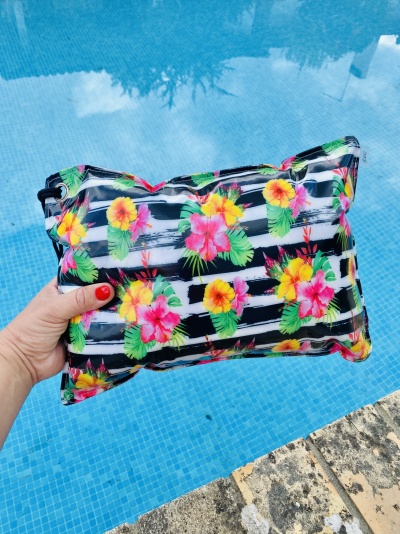 Mala colorida com padrão floral e listras preta e branca junto à piscina