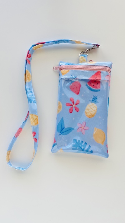 Estojo azul claro com padrão de frutas e flores coloridas, com alça e fecho rosa.