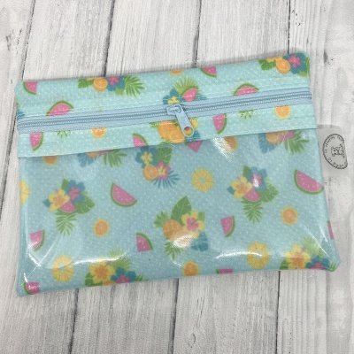 Saco tecido azul claro com padrão de frutas tropicais e fecho zip azul.