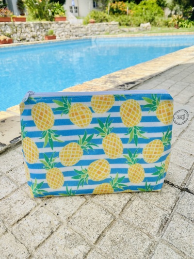 Necessaire com padrão de abacaxis e riscas azuis junto à piscina