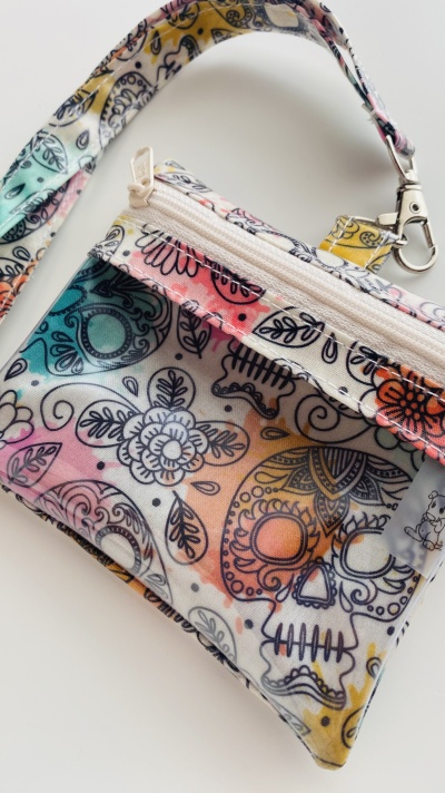 Bolsa pequena com padrão colorido de caveiras e flores