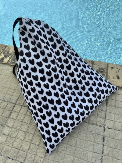 Bolsa saco branca com corações pretos junto a piscina