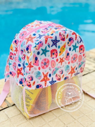 Mochila infantil colorida com padrão marinho junto a piscina