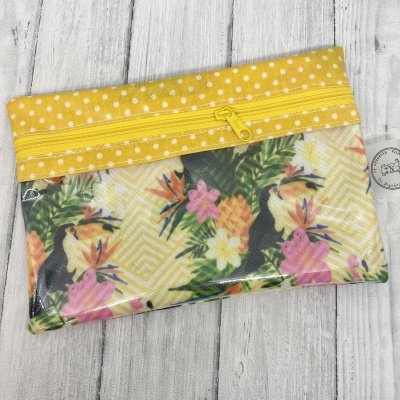 Necessaire retangular amarela com padrão de bolinhas e flores, com fecho de correr.