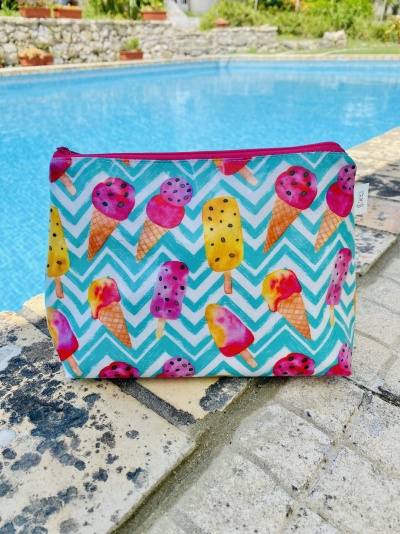 Necessaire com padrão de gelados coloridos em fundo azul e branco junto a piscina